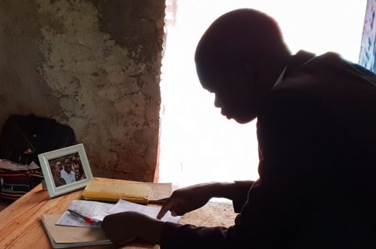 Jean-Aimé examines a document at a desk