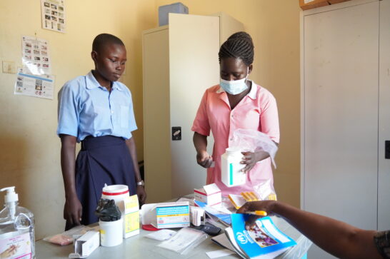 A nurse in a public health facility dispensing medicines to a student.