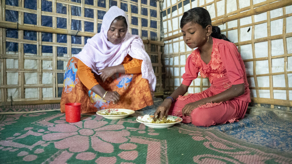 A Rohingya mother and a daughter eating in Cox's Bazar.