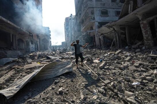 A man in the street in Gaza that has been destroyed by bombings.