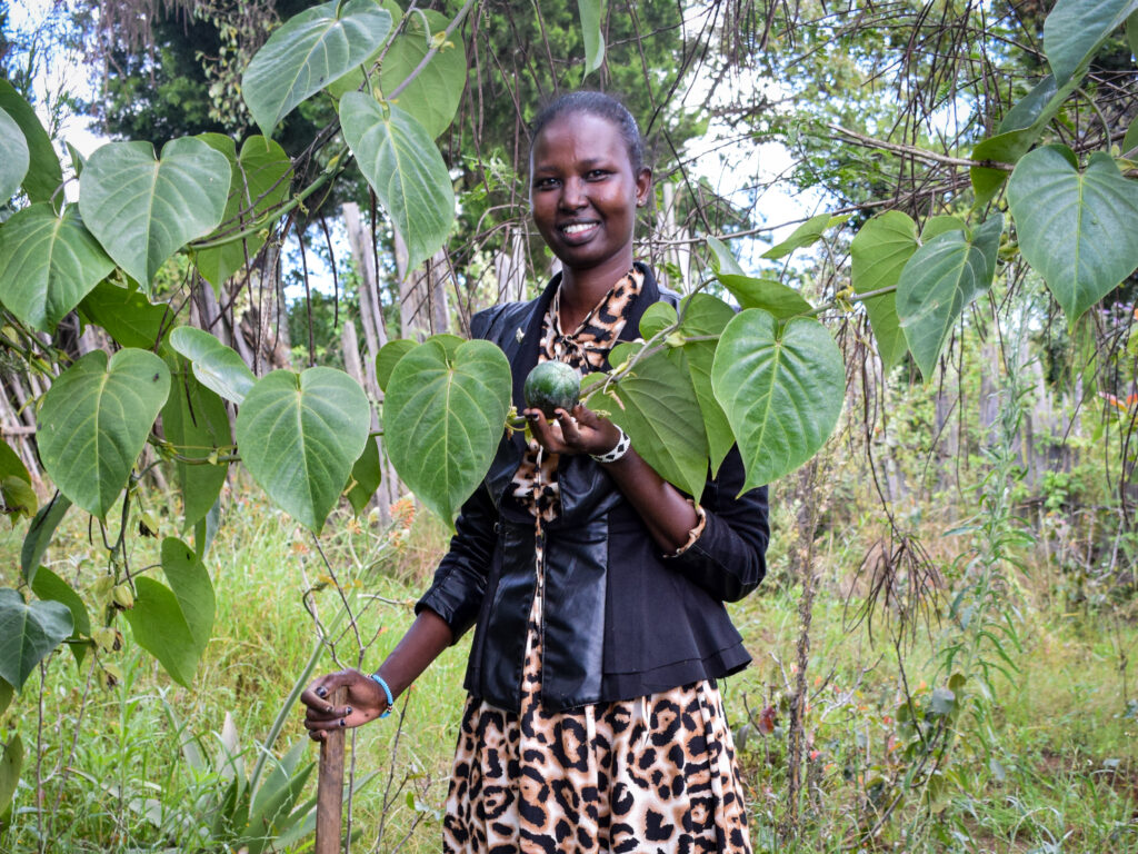 A Kenyan woman holding a fruit.