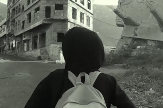 Young girl walking through the ruins of a Yemeni town.