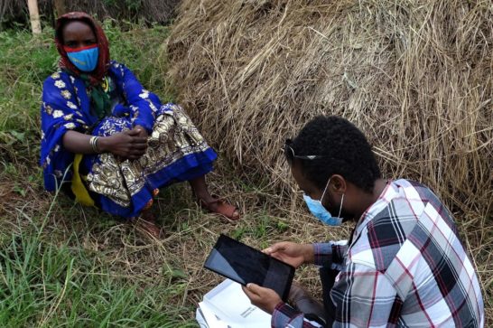 a man, seated, conducts a digital rapid needs assessment asking questions to a woman and storing data on his tablet. Image: Cordaid
