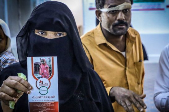 woman shows health care brochure about the importance of psychological support for children. Man whose head has a bandage in the background