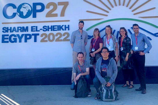 a group of men and women in fron of the climate summit banner in Egypt