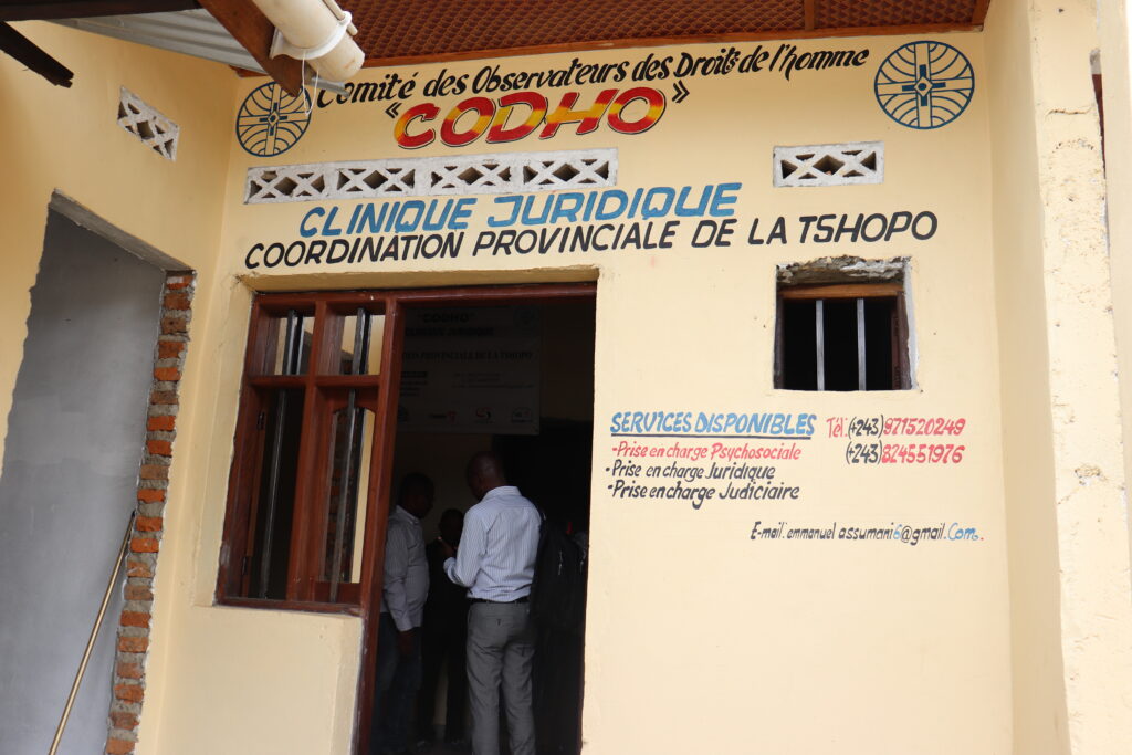 yellow facade of a building with an open door and on the wall it says 'legal clinique' in French