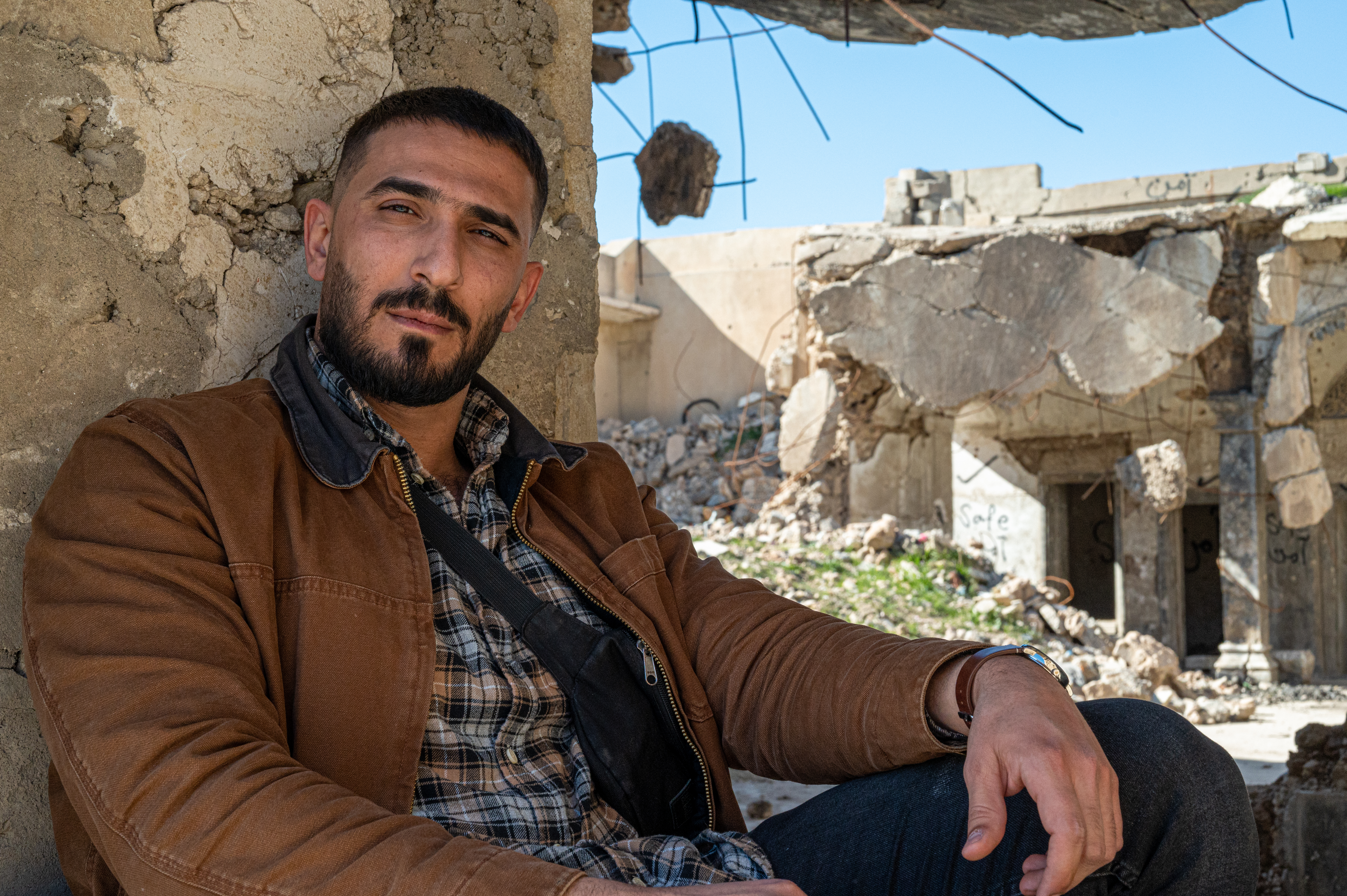 man sitting in front of a destroyed building