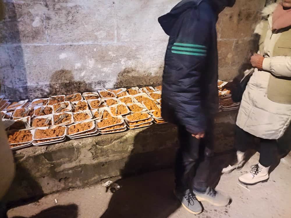 lots of prepared meals on plates on a stone bench outside