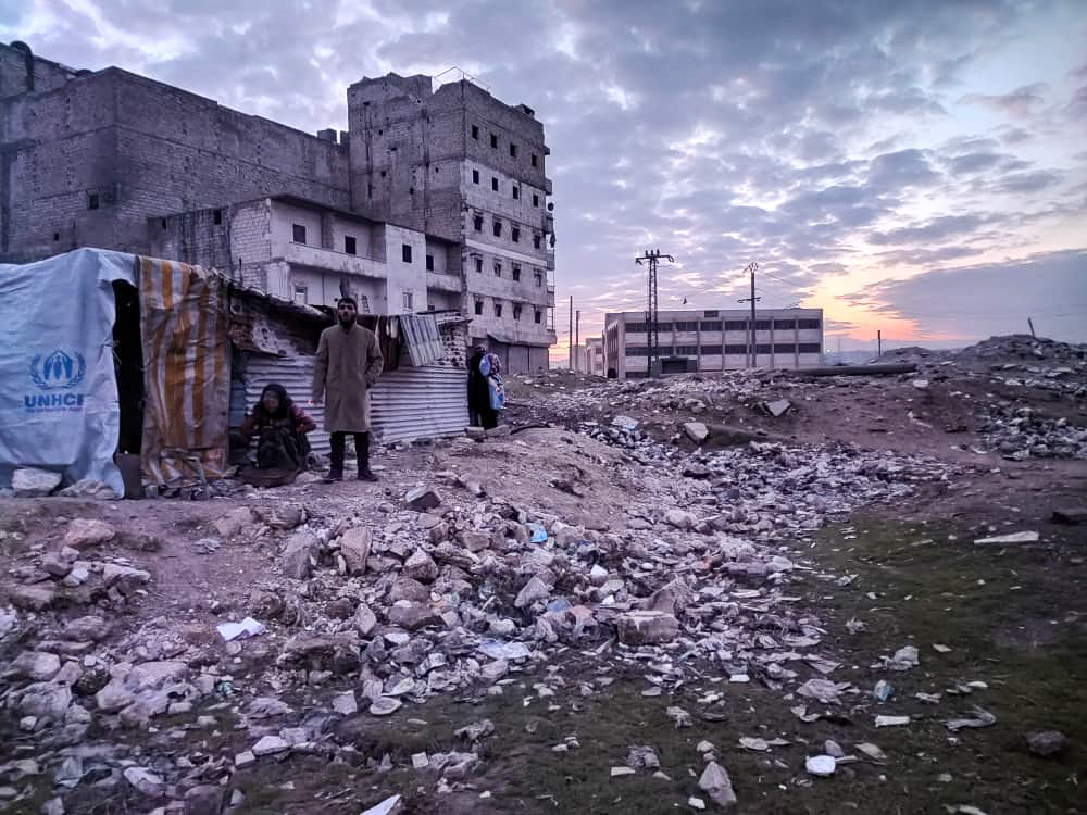 rubble and a shack and people in front