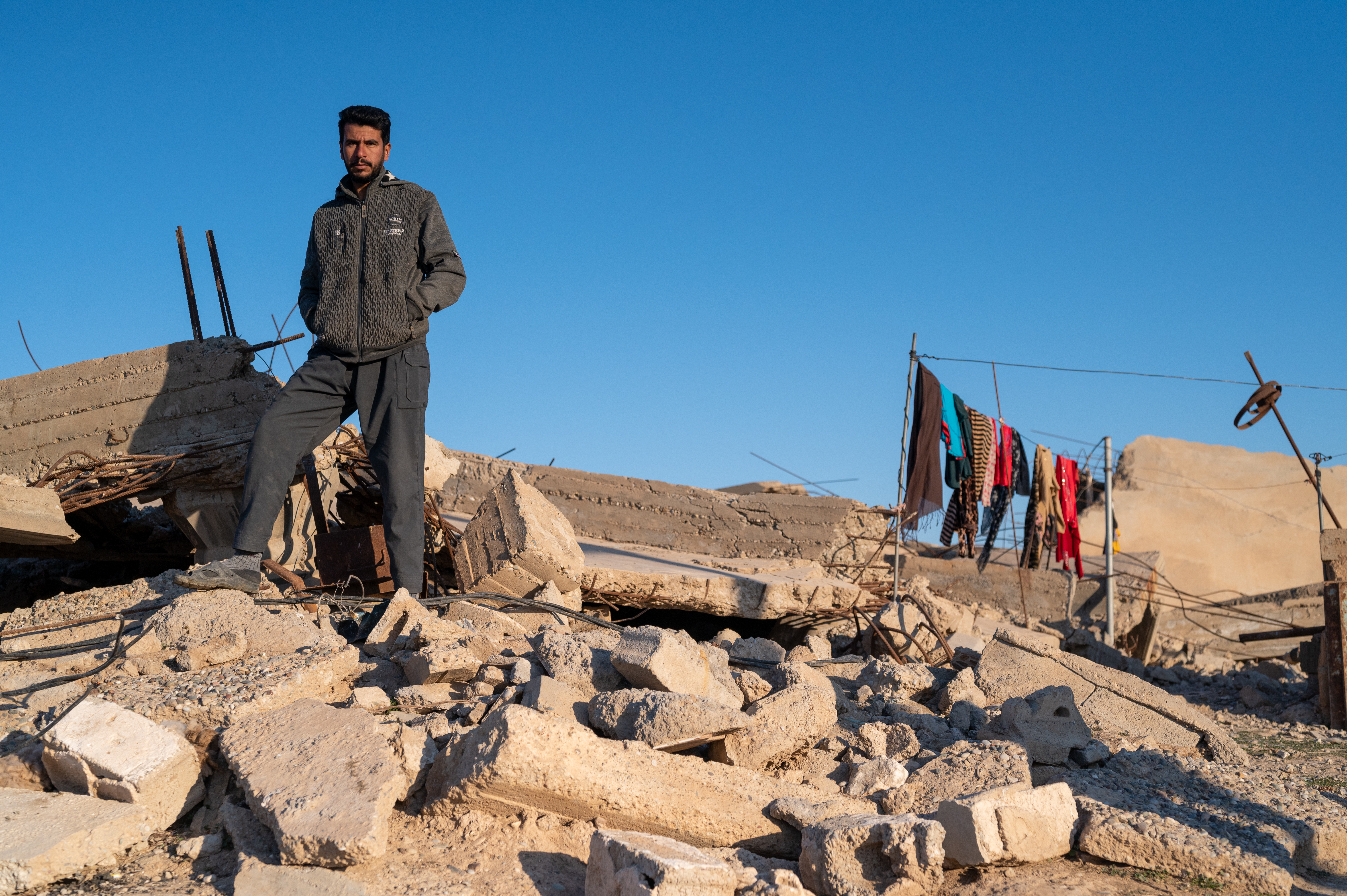 man on pile of rubble clothes drying