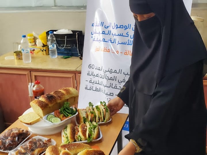 Yemeni woman and holding a plate full of sandwiches.