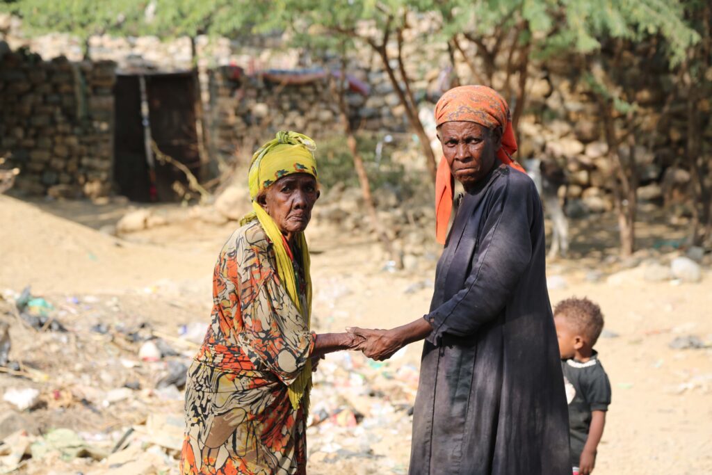 Two elderly Yemeni women holding hands.