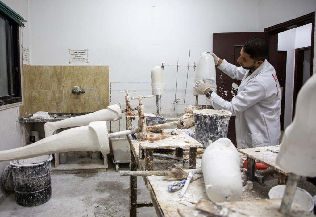 man in witte stofjas aan het werk met gips in een atelier