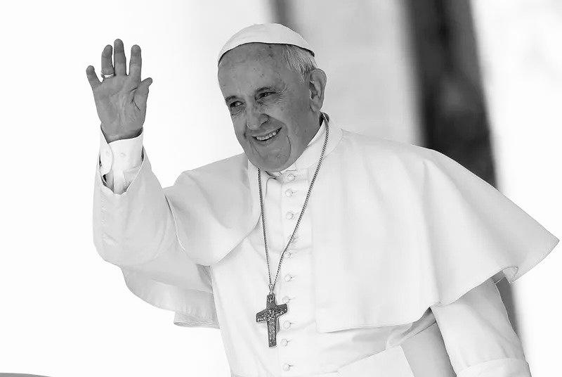 Paus Franciscus in witte pauselijke gewaden, glimlachend en zwaaiend tijdens een publieke verschijning.