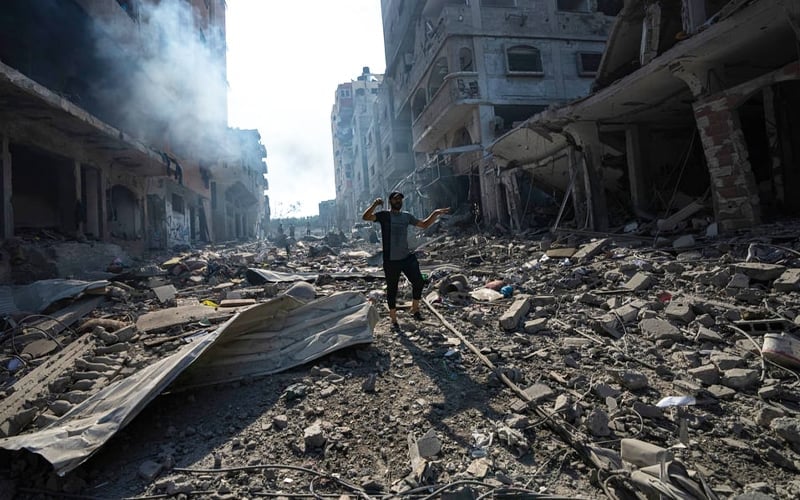 Een man in een door bombardementen verwoeste straat in Gaza.