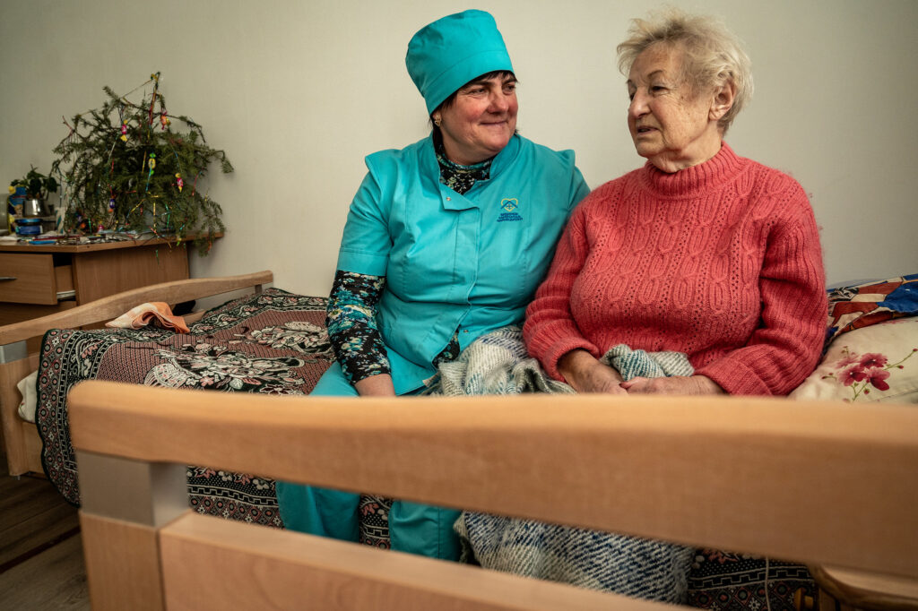 Oekraïense verpleegkundige en oudere in een opvangcentrum.
