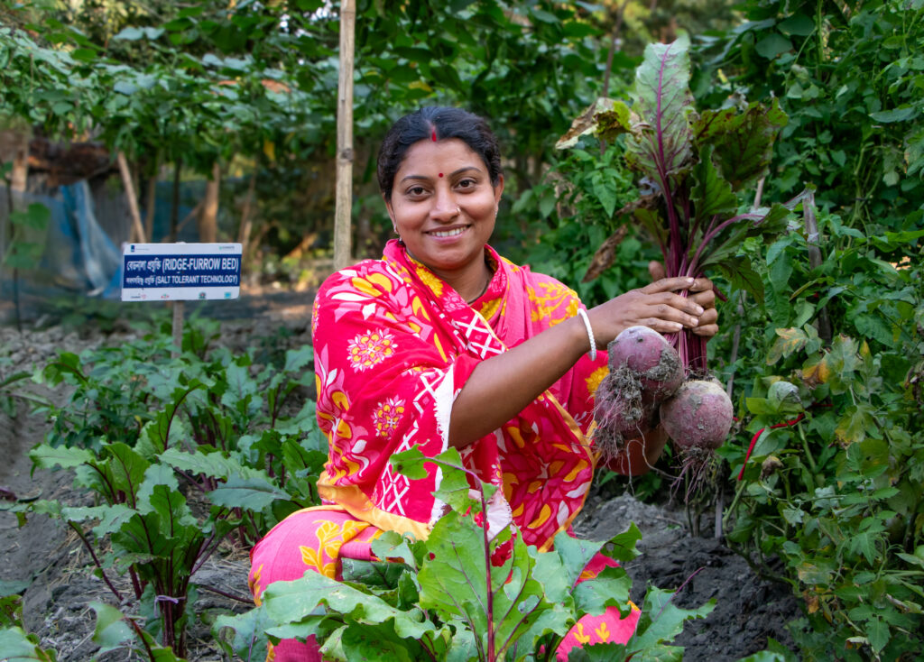 Uma Roy, een kleinschalige boerin uit Zuid-Bangladesh en COASTS-deelneemster, houdt trots en blij een deel van haar oogst (bieten) vast. COASTS wordt mede mogelijk gemaakt door de Rijksdienst voor Ondernemend Nederland. En is een publiek-privaat partnerschap bestaande uit Lal Teer Seeds Ltd, Soil Resource Development Institute van het Bengaalse Ministerie van Landbouw, Bangladesh Agricultural University en Cordaid.