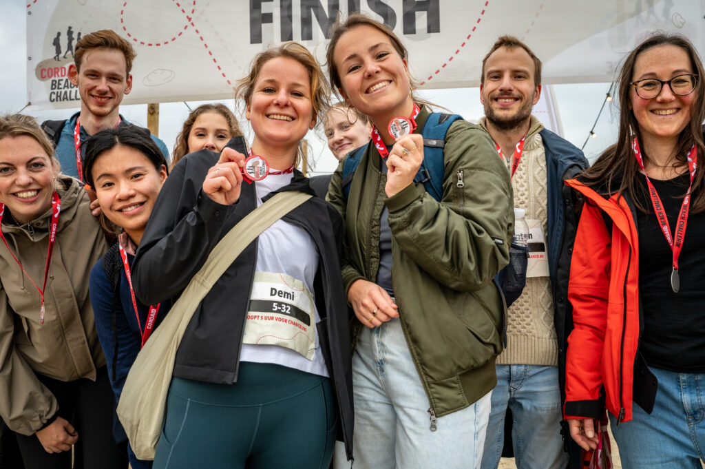 Deelnemers Cordaid Beach Challenge 2025 laten blij medaille zien bij finish