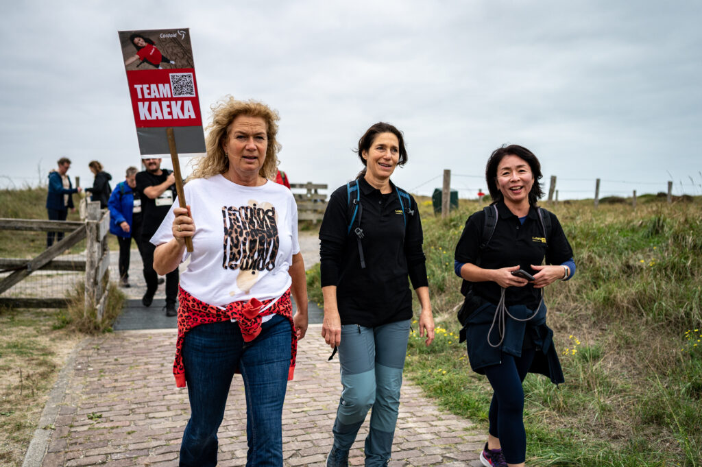 Wandelaars Cordaid Beach Challenge 2025 met bord Team Kaeke in duinen Scheveningen