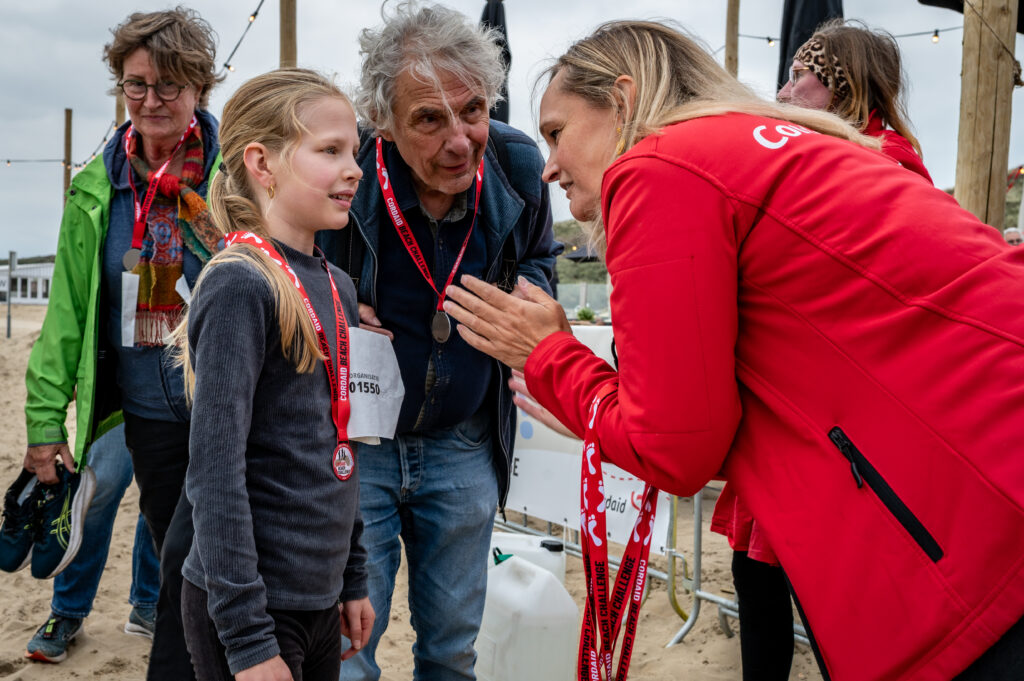 Directeur Cordaid Heleen van den Berg geeft jonge deelnemer Cordaid Beach Challenge 2025 een medaille - Foto: Mickael Franci