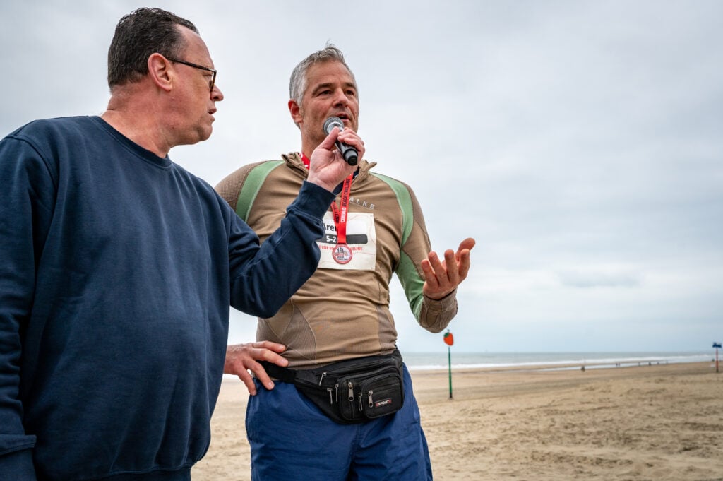 Cordaid Beach Challenge 2025: presentator Edwin Koene interviewt deelnemer op een podium op het strand