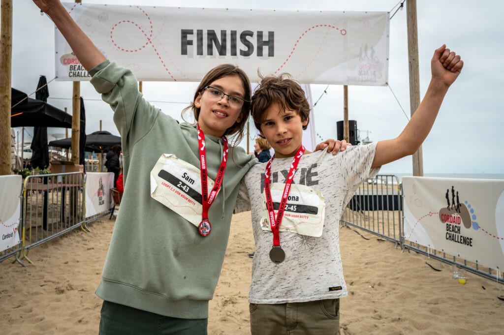 Twee jonge wandelaars Cordaid Beach Challenge 2025 blij bij finish