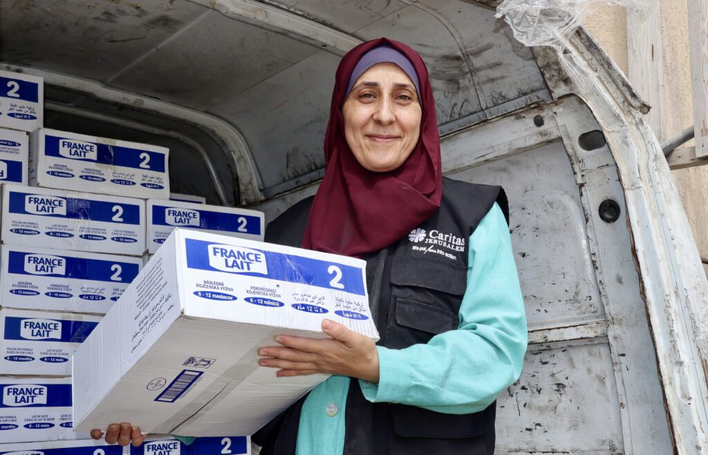Medewerker partner Cordaid poseert met groot pak vol babyvoeding in Gaza