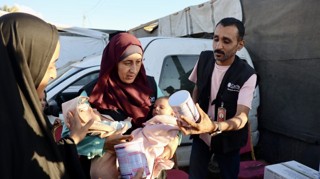 Medewerker van partner van Cordaid Caritas Jerusalem deelt blikken babyvoeding uit in Gaza.