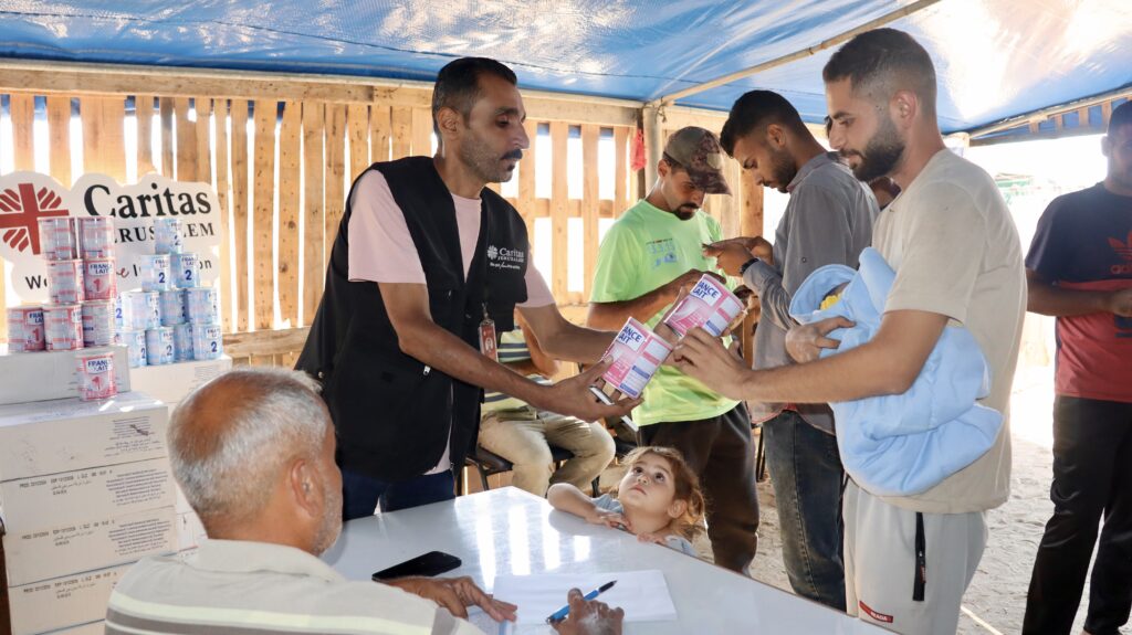 Medewerker partner Cordaid Caritas deelt blikken babyvoeding uit in een tent in Gaza.