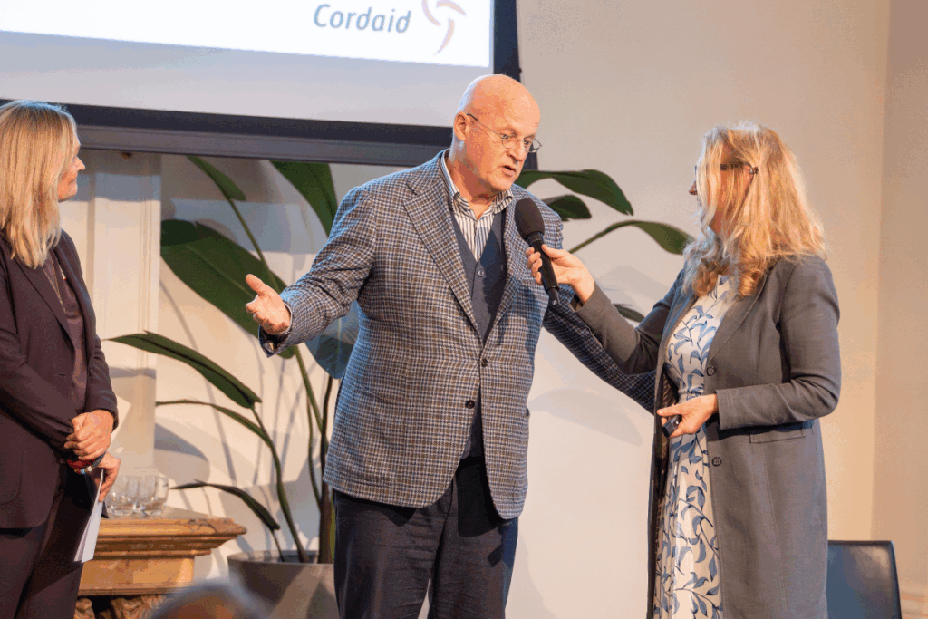 Ferd Grapperhaus lid van Raad van Toezicht Cordaid op podium bij 100-jarig jubileum gezondheidswerk Cordaid