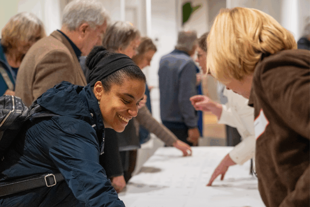 Mensen staan bij de aanmeldbalie van 100-jarig jubileum gezondheidswerk Cordaid