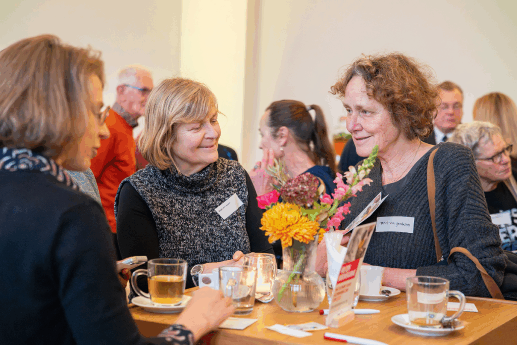 Bezoekers genieten van kop thee tijdens pauze 100-jarig jubileum gezondheidswerk Cordaid